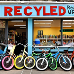 **

A bright, modern workshop showcasing artisans crafting jewelry from recycled materials like colorful plastic scraps and repurposed bicycle tires. Emphasize transparency with visible material sourcing information (e.g., a small sign indicating "Recycled Plastic from Local Beach Cleanups").

**